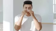 Man sneezing into tissue from allergy
